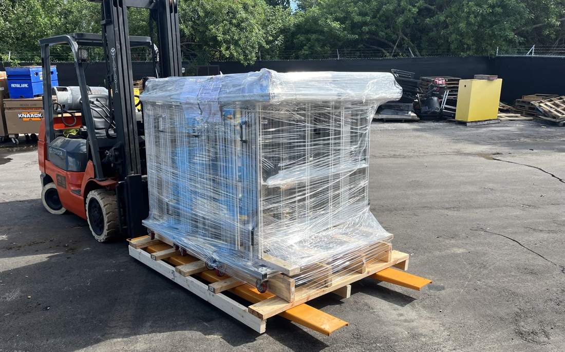 Finished machine stretch-wrapped on a skid and loaded on a forklift