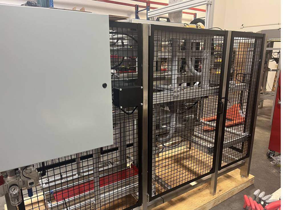 Grey control enclosure mounted beside black mesh guarding