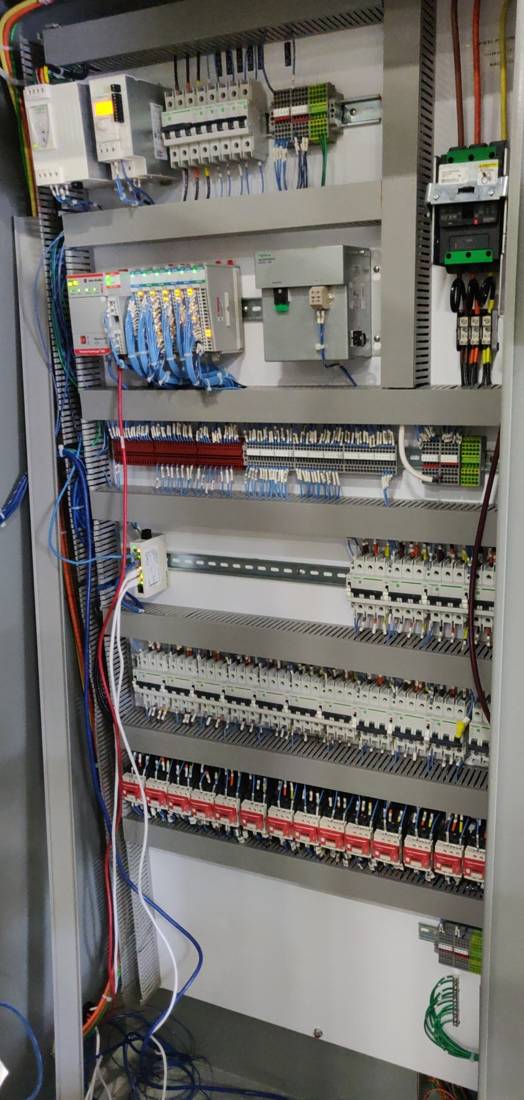 Floor-standing control panel with PLC, IO, terminal rows, breakers and motor protection
