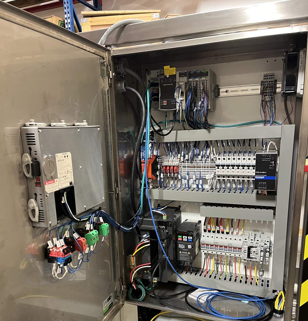 Open stainless control panel with PLC, servo drive, VFD, power supply and a pneumatic valve enclosure below
