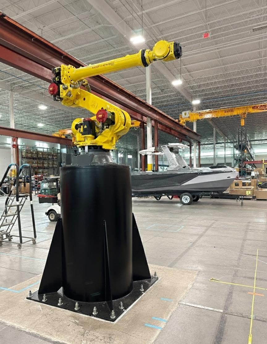 Yellow FANUC R-2000iC robot mounted on a black Robot Risers pedestal
